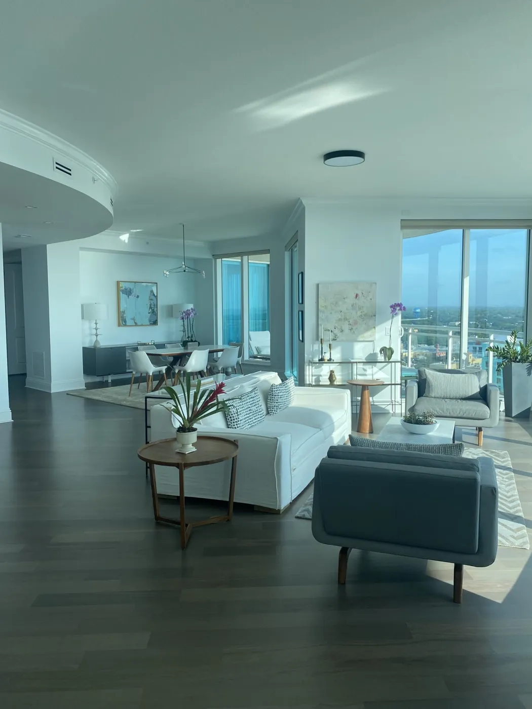 Condo living room with white sofas and dark wood floors